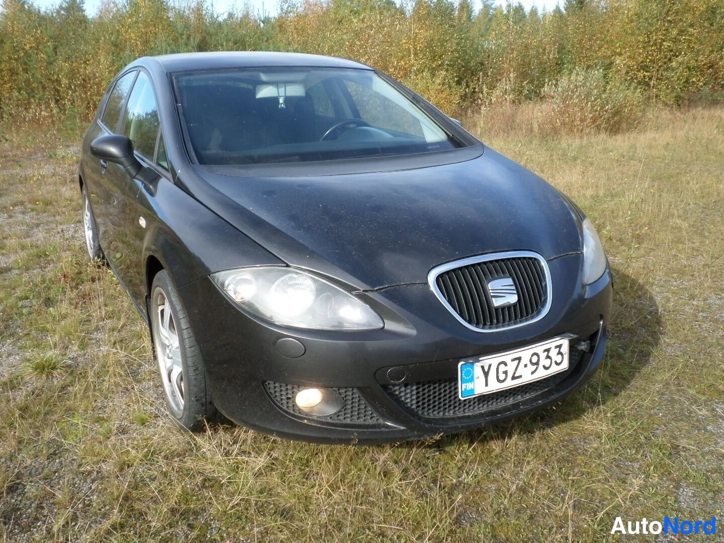 Etuviisto, nokka oikealle: Musta henkilöauto edestä oikealta kolmenvälin kuvakulmassa, rekisteritunnus.