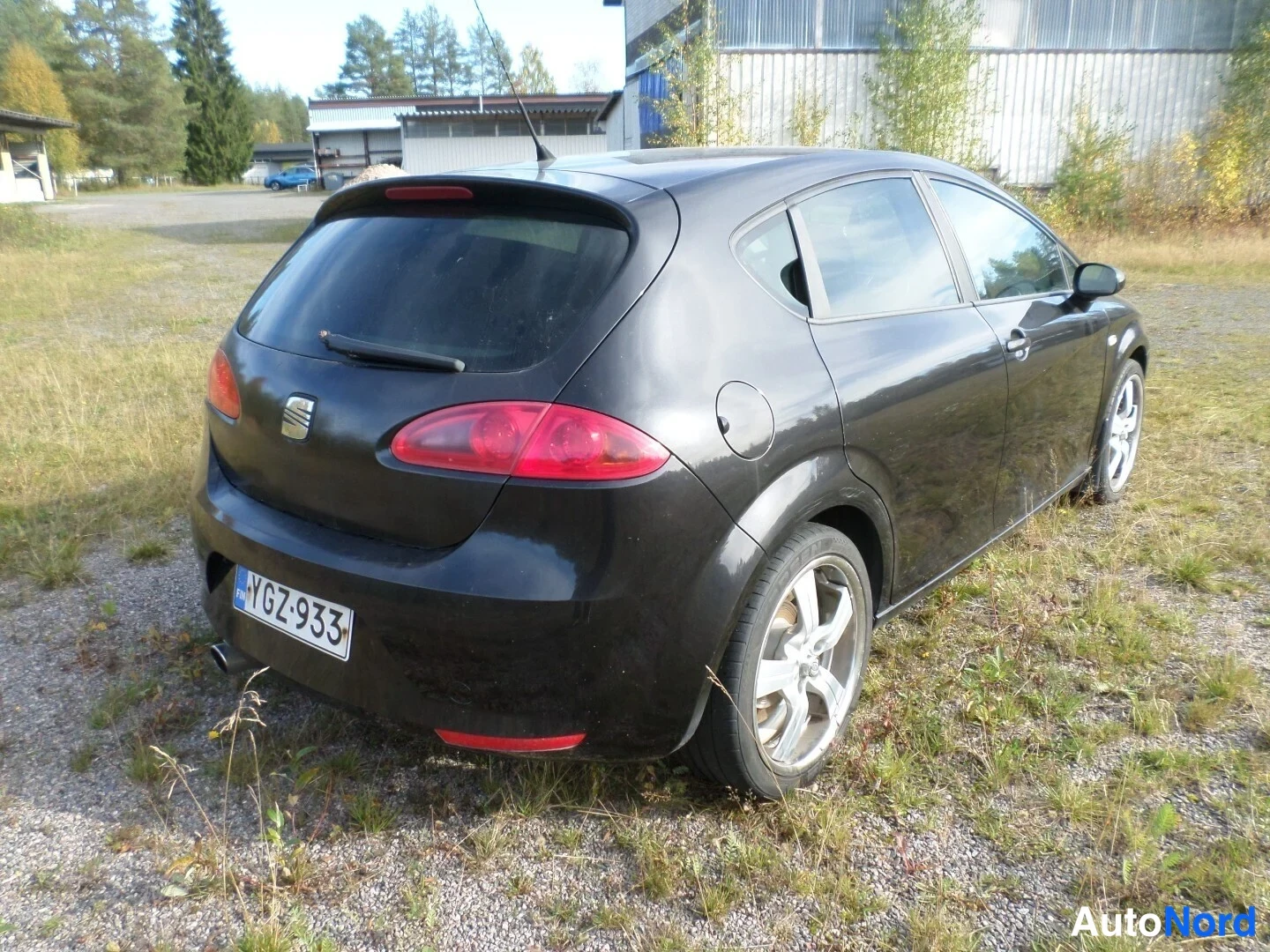 Takaviisto: Musta henkilöauto takaa oikealta kolmenvälin kuvakulmassa, rekisteritunnus.