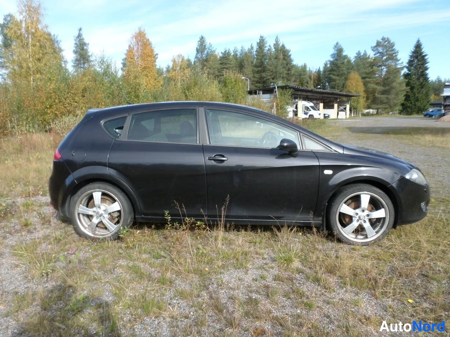 Etuviisto, nokka oikealle: Mustan henkilöauton etukulma oikealta, viisiovinen hatchback sorapintaisella alueella.