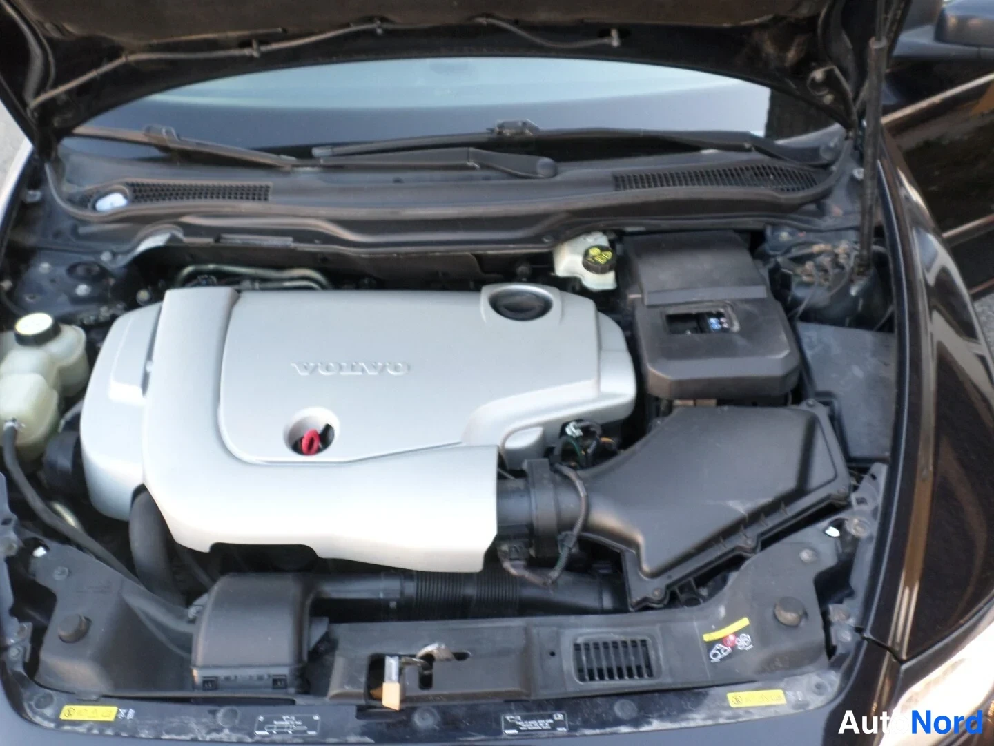 Moottoritila: Engine bay view showing a silver engine cover with 'VOLVO' embossed on it.