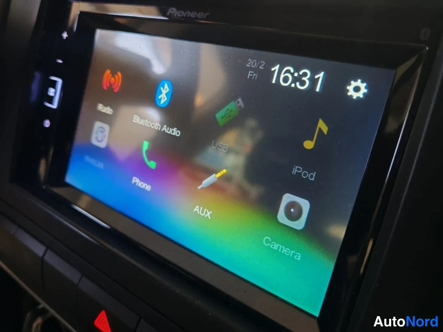Yksityiskohta: Infotainment screen displaying main menu icons including USB, iPod, AUX input connections available.