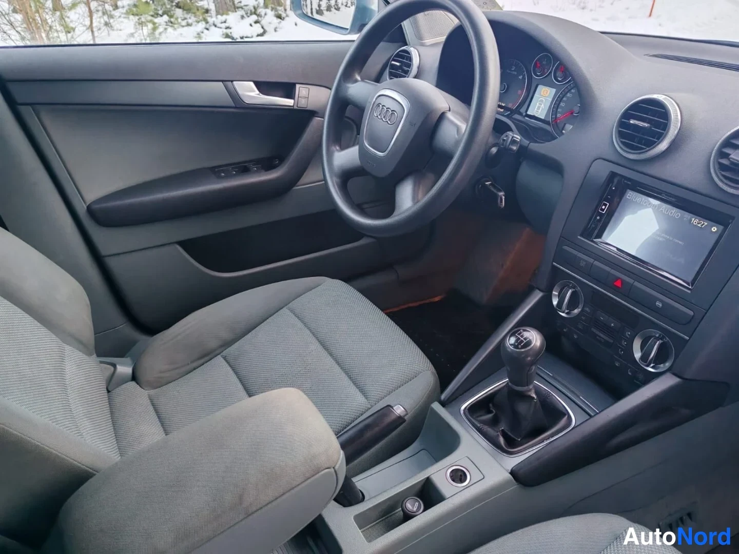 Muu: Audi A3:n ohjaamotila kuljettajan puolelta: Audi-ohjauspyörä, manuaalivaihteisto ja kangasistuimet.