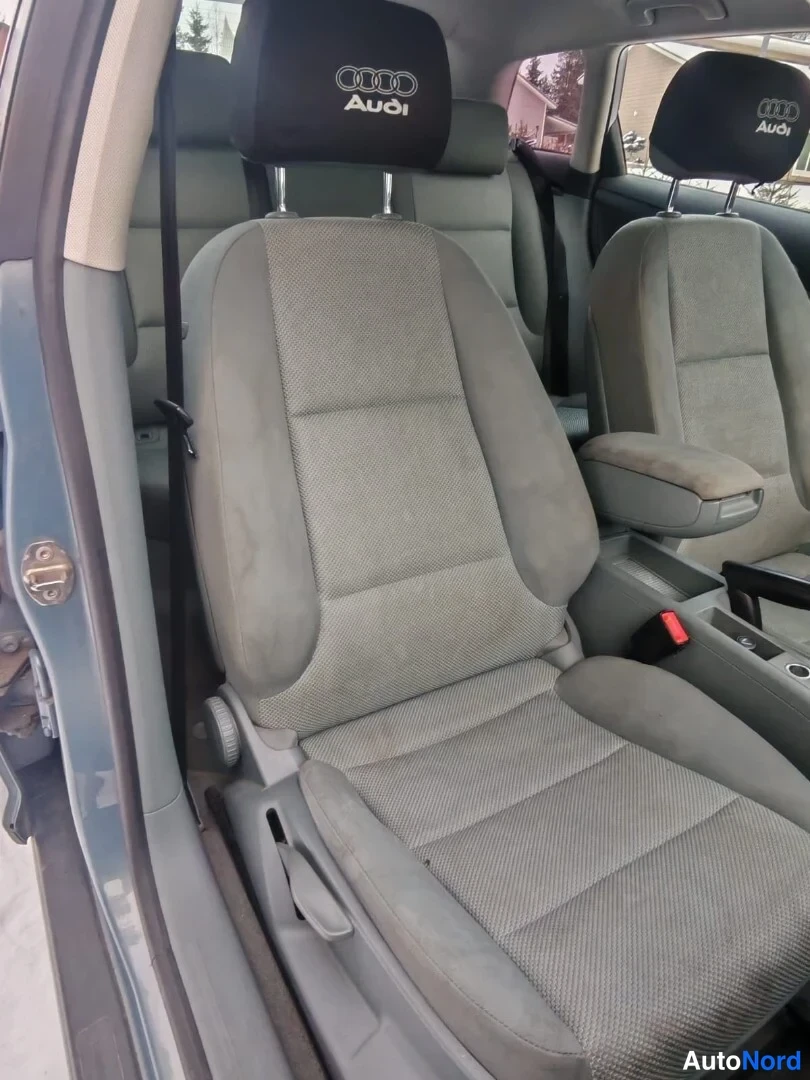 Muu: Audi A3:n etuistuin ja kaksiosainen takaselkänoja näkyvät avatun kuljettajan oven takaa; istuinten headrest-päineen lävistää Audi-logo.