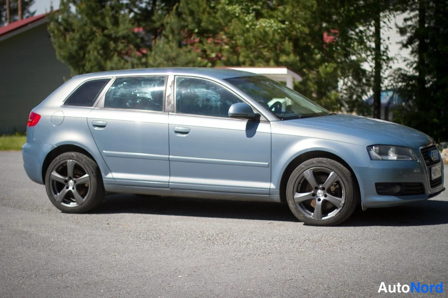 Sivulta: Side profile of the light blue station wagon parked on asphalt. Both wheels and doors are visible.