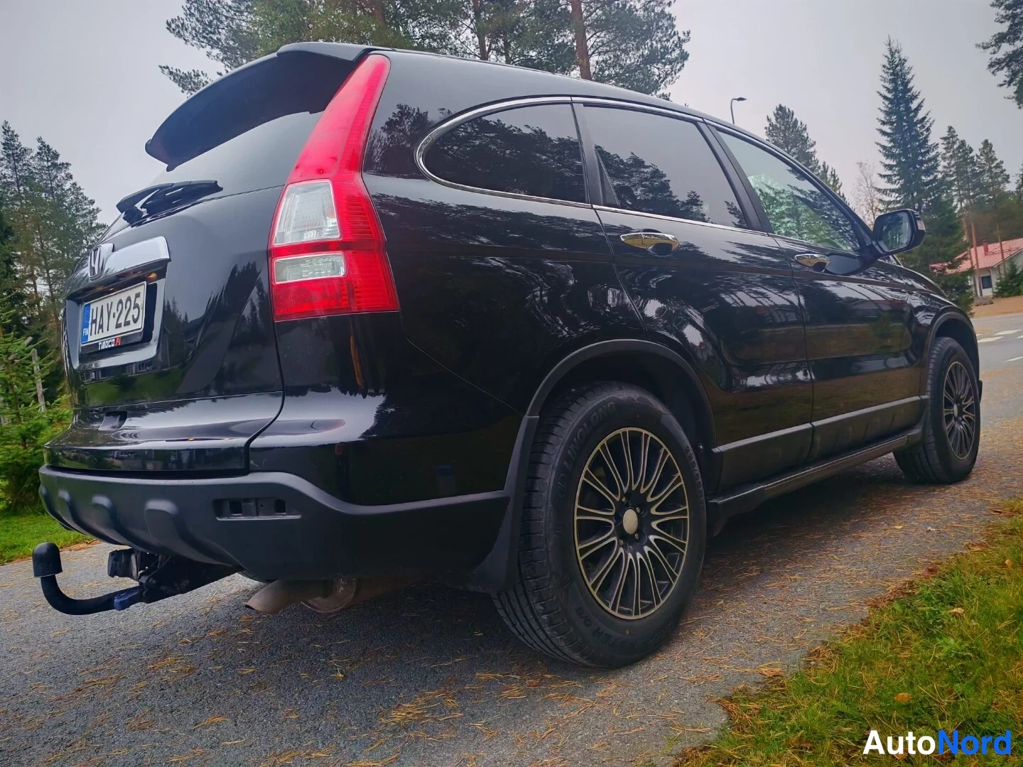 Takaviisto: Mustan Honda CR-V:n takakulma kylki ja takaosa näkyvillä, mustat alumiinivanteet ja vetokoukku.