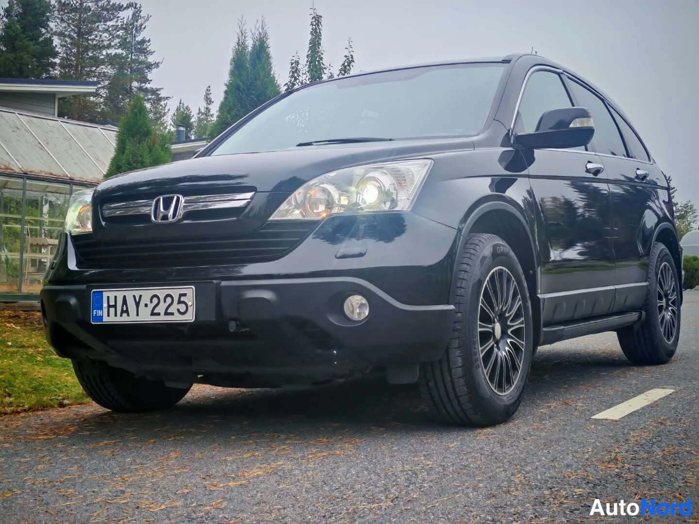 Etuviisto, nokka vasemmalle: Musta Honda CR-V kolmivärikuvassa edestä vasemmalta, rekisteritunnus.