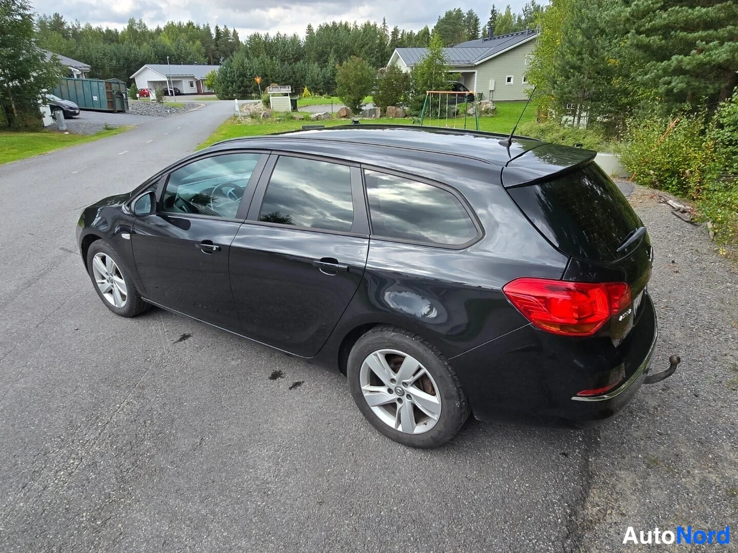 Takaviisto: Musta farmariauto kuvattu takaa sivusta, takaosa ja oikea kylki näkyvissä.