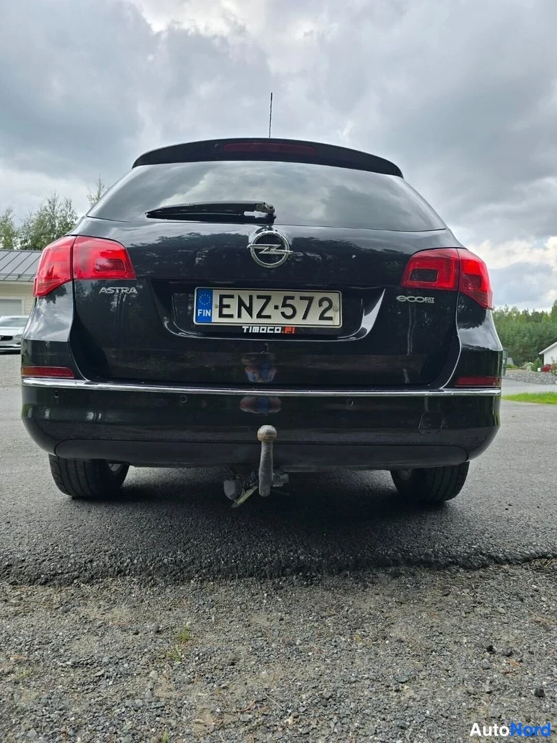 Takaa: Opel Astra Sports Tourer musta takaa kuvattuna, rekisterikilpi, ECOflex-tarra ja TIBOCO-32-kyltti takaovessa.