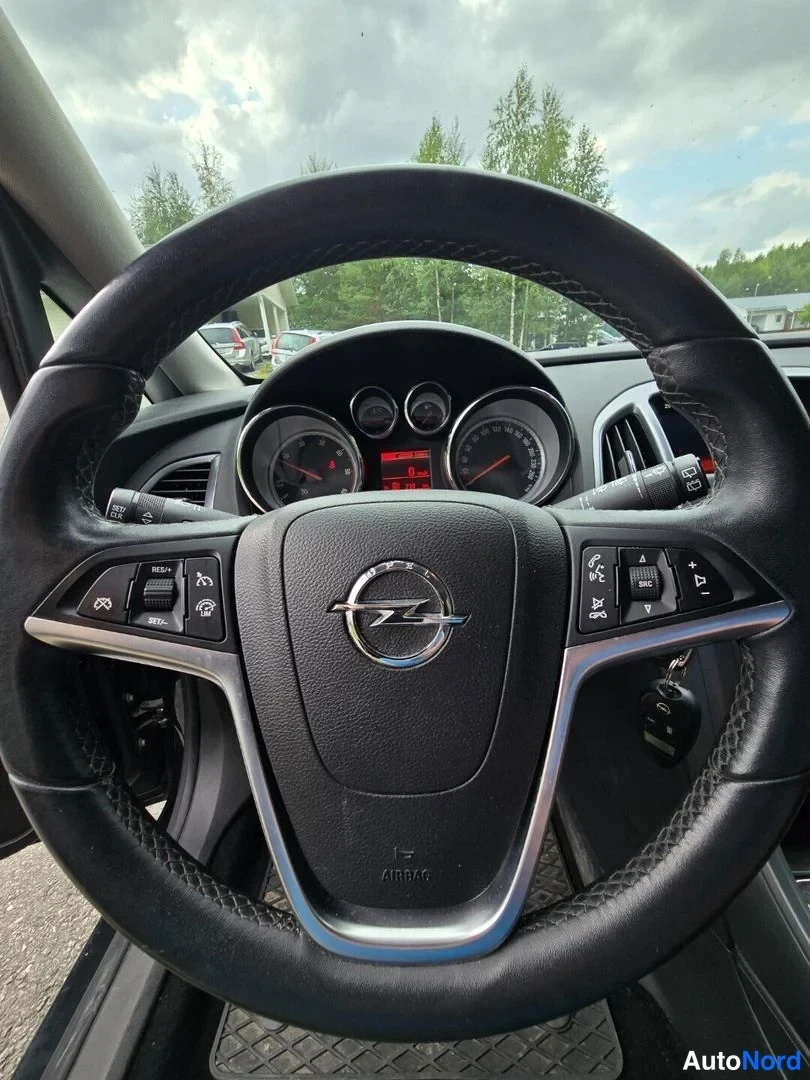 Muu: Opel-merkkinen ohjauspyörä ja kojelauta kuvattuna kuljettajan paikalta; pyörän molemmin puolin monitoiminapit.