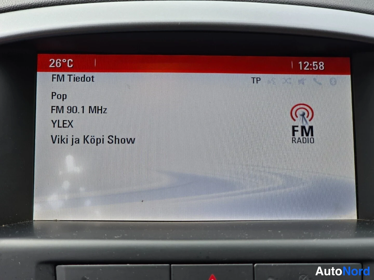Muu: Auton näyttö, jossa radiokanava YLEX FM 90.1 MHz, lämpötila 26 °C ja kello 12:58.