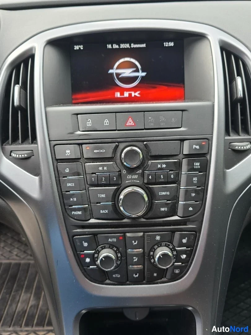 Muu: Auton kojelaudan keskikonsolin lähikuva. Ylhäällä infotainment-näyttö, jolla lukee '28°C', '16. Elo. 2026, Sunnuntai', '12:56' sekä Opel-logon alapuolella tekst