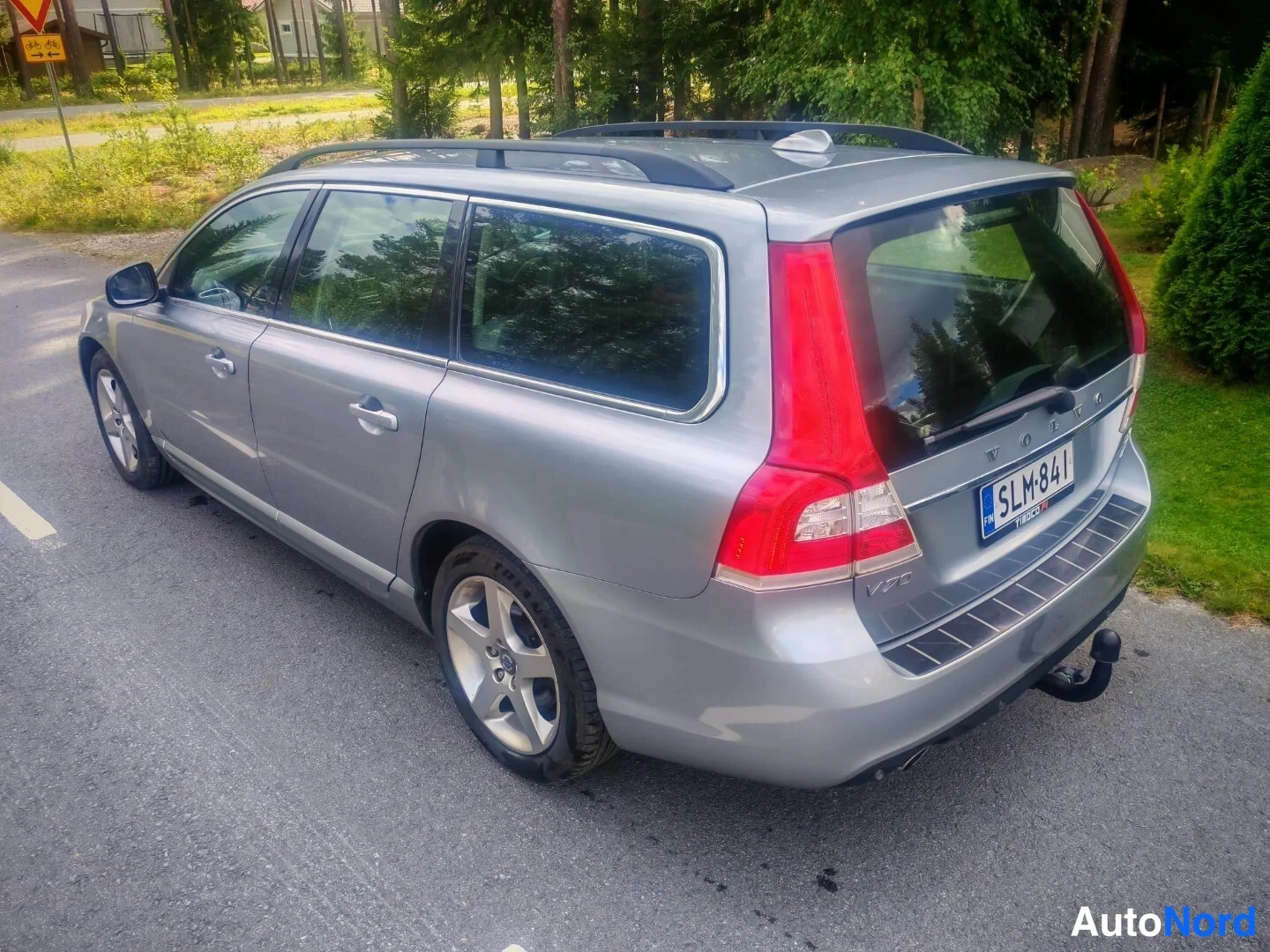 Takaviisto: Hopeanharmaa V70-asema-auto takaa oikealta kolmanneltasektorilta, rekisterikilpi, tavaratilan kattotankot, takavalo punainen, lukkokeko takaossa.