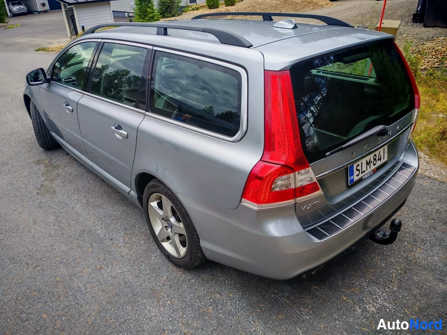 Takaviisto: Hopeanharmaa farmariauto yläviistosti takaa sivulta kuvattuna, kattokaiteet ja rekisterikilpi näkyvät.