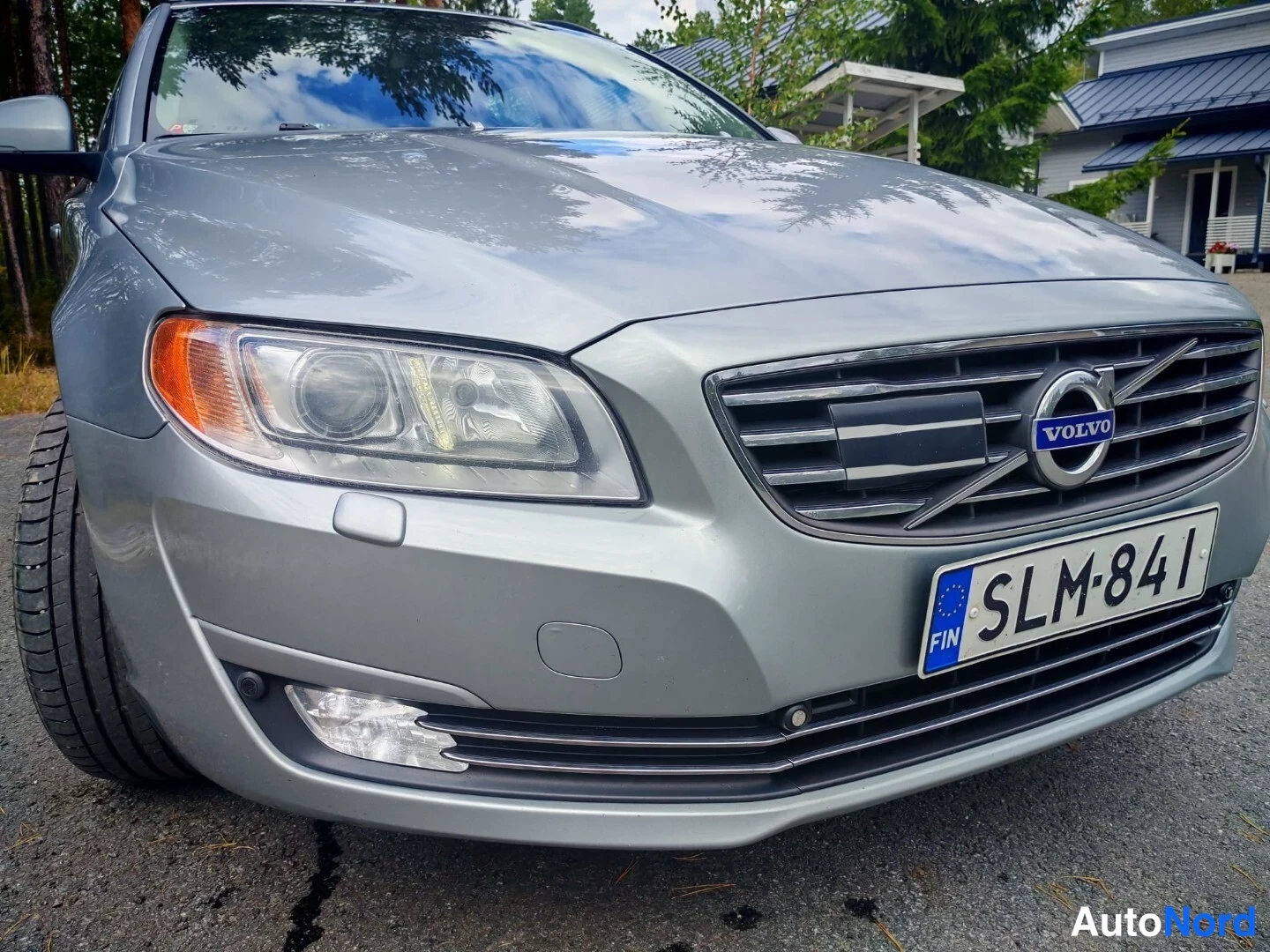 Edestä: Lähikuva auton etuosasta: harmaan Volvon etukalusto, Volvo-logo, rekisterikilpi, etuvalo ja sumuvalot. Kalustossa on vaakasuorat raidat. Vasemmalla näkyy osa re