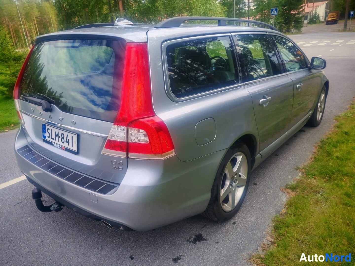 Takaviisto: Side-rear view of a silver Volvo V70 showing the rear door, wheel, tail light and roof rails while parked outdoors