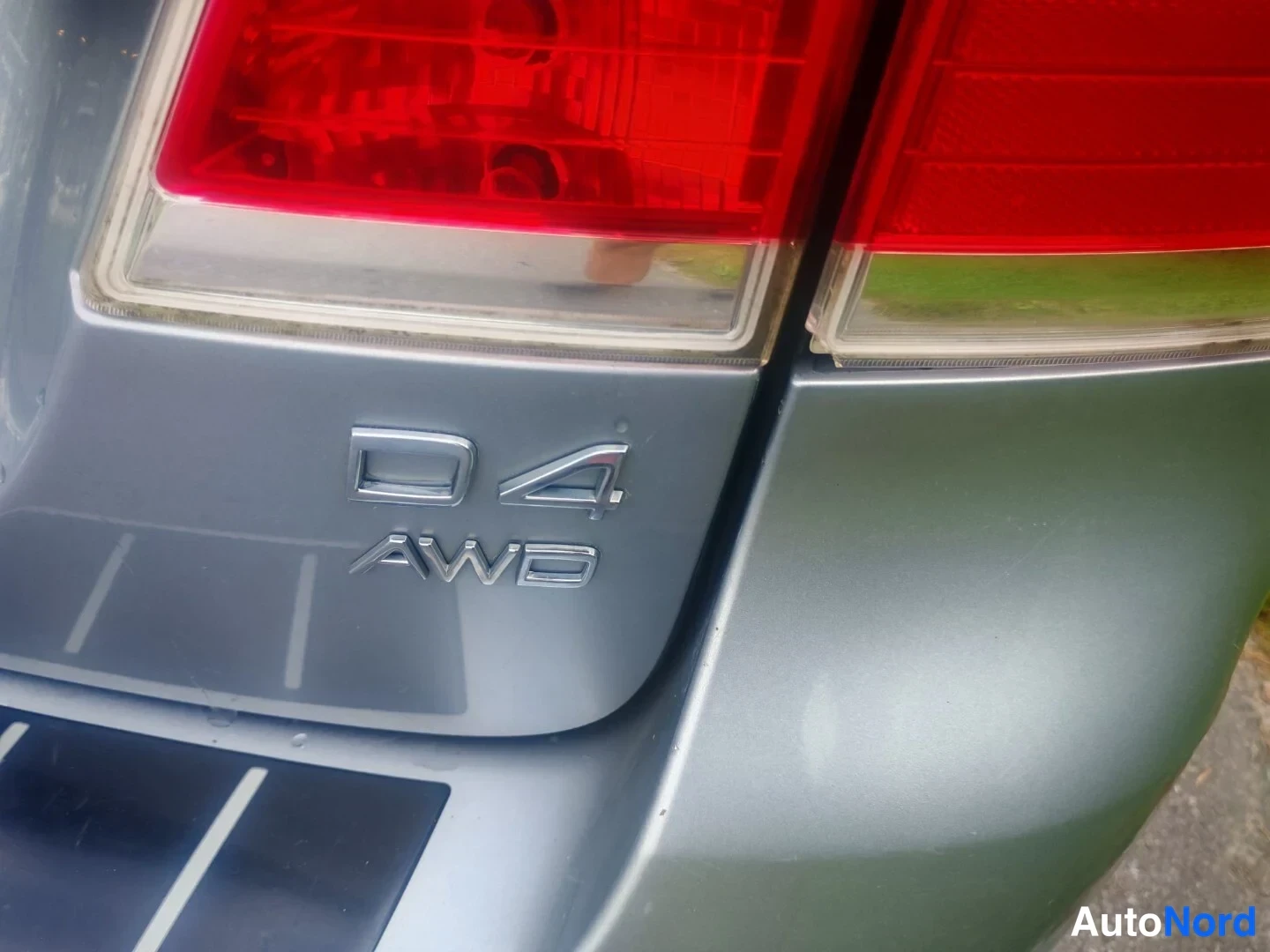 Yksityiskohta: Close-up of the vehicle's rear badge area displaying the chrome 'D4' and 'AWD' emblems between the red tail lamps