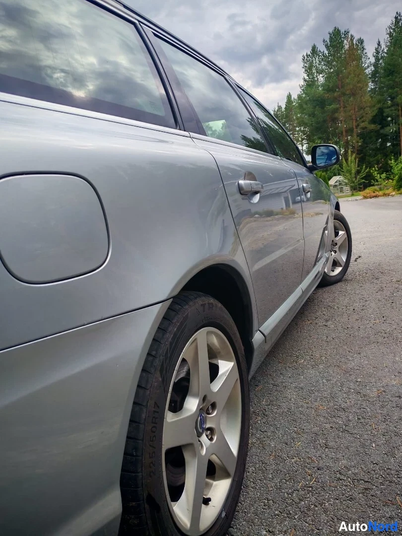 Sivulta: Hopeanharmaan auton vasen kylki lähikuvassa, takapyörä ja tankin täyttöaukko näkyvissä.