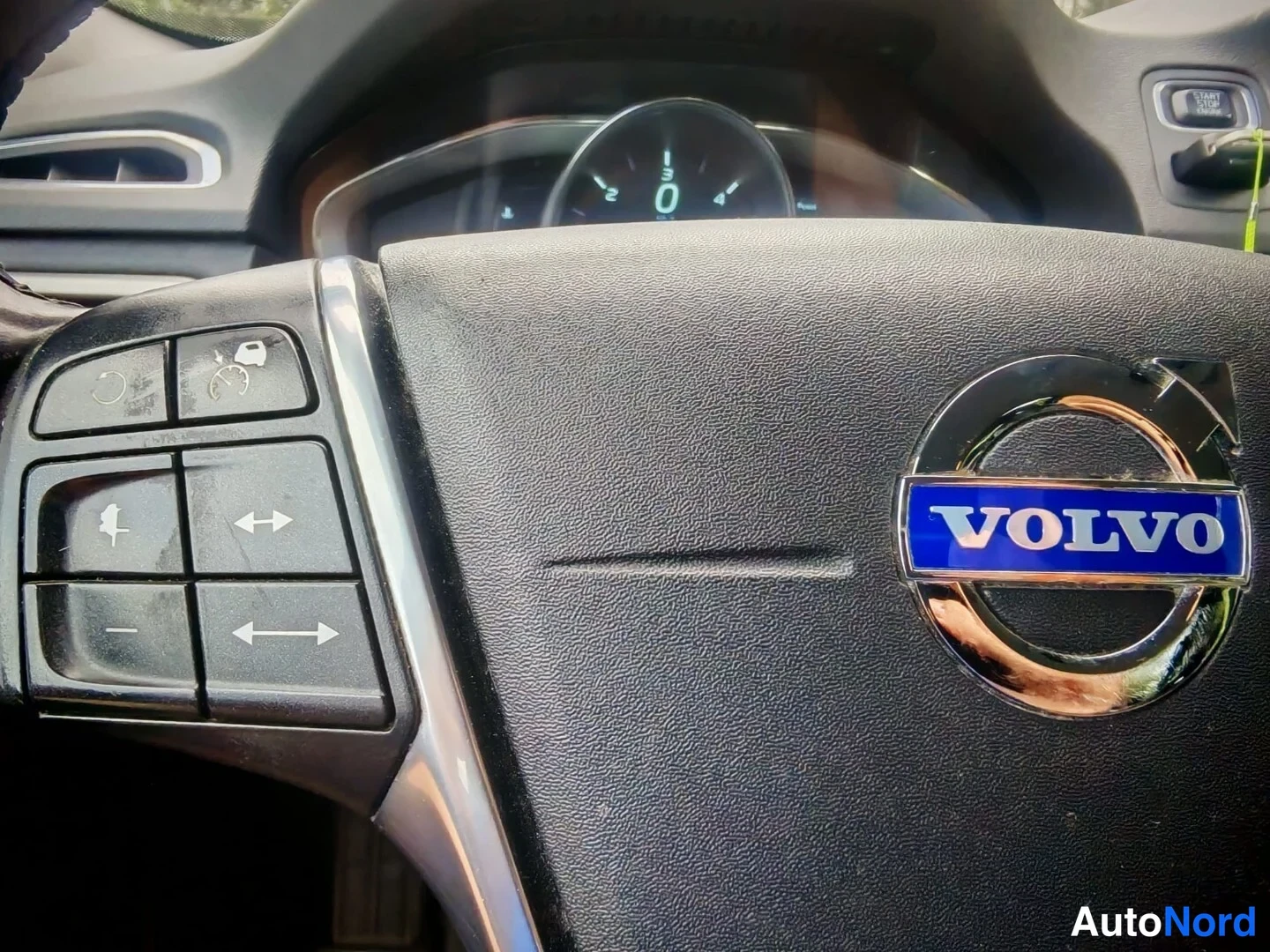 Muu: Volvo-ohjauspyörän vasen pöydällinen haltioiden ja pyörän keskellä oleva VOLVO-merkki, taustalla mittaristo.