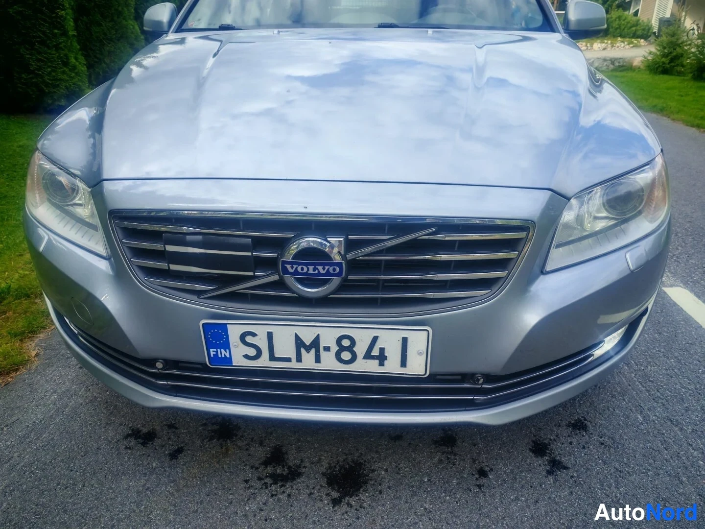 Edestä: Suora etänäkyvä hopeanharmaan auton keulasta; VOLVO-merkki jäähdyttimeen, etuvalot ja rekisterikilpi FIN näkyvät.