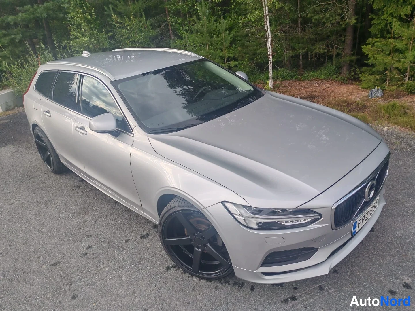 Etuviisto, nokka oikealle: Hopeanharmaa farmariauto kolmeneljännesnäkulmassa edestä vasemmalta, mustat vanteet ja kattokaiteet näkyvät.