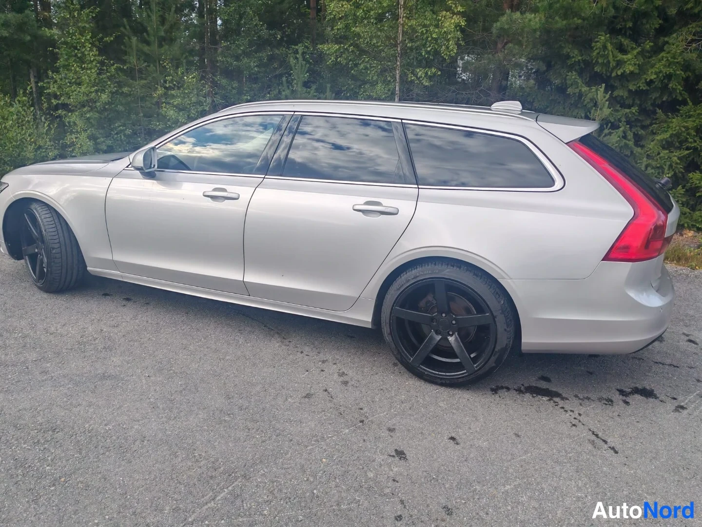 Sivulta: Silver Volvo estate captured from driver-side angle showing complete side silhouette with black alloy wheels, door handles and rear taillight assembly