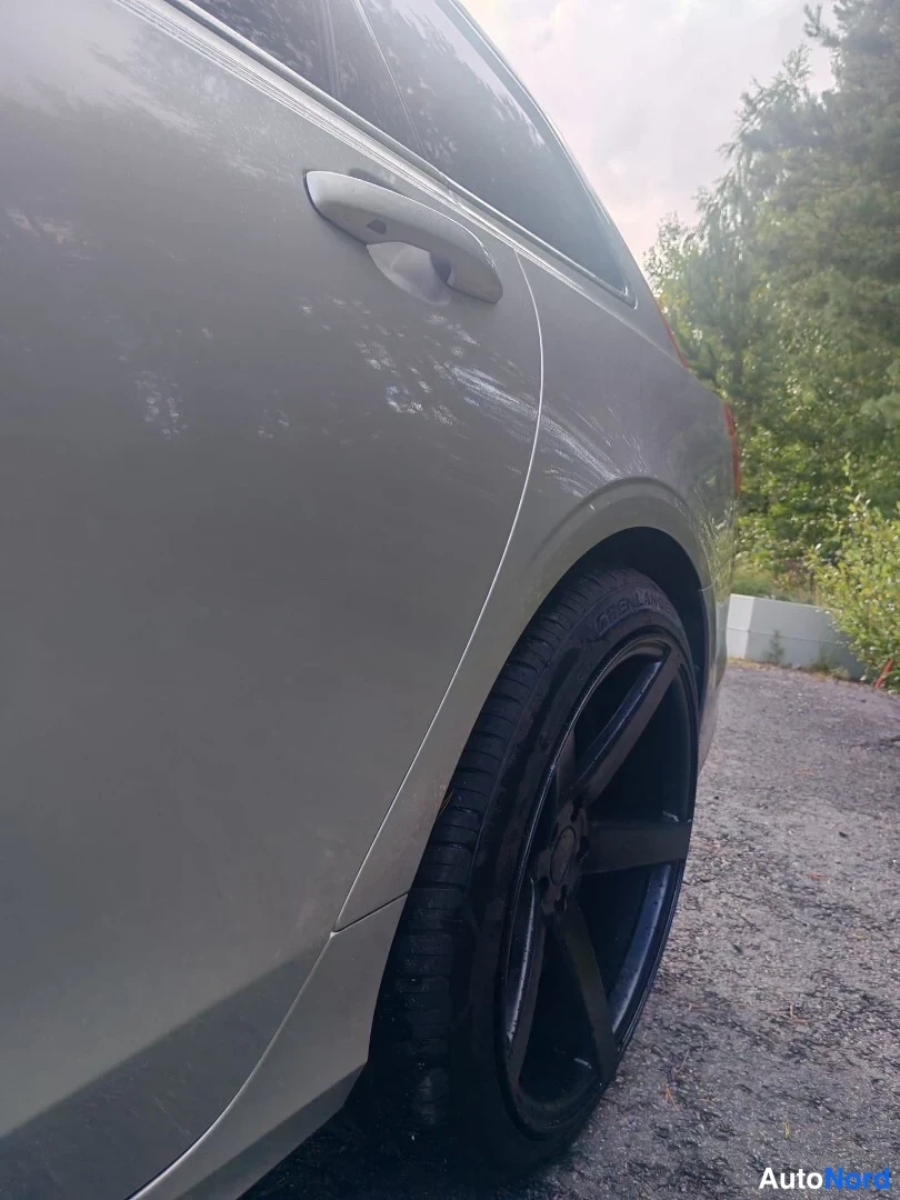 Yksityiskohta: Close-up of silver rear door panel and black five-spoke alloy wheel with tire tread details
