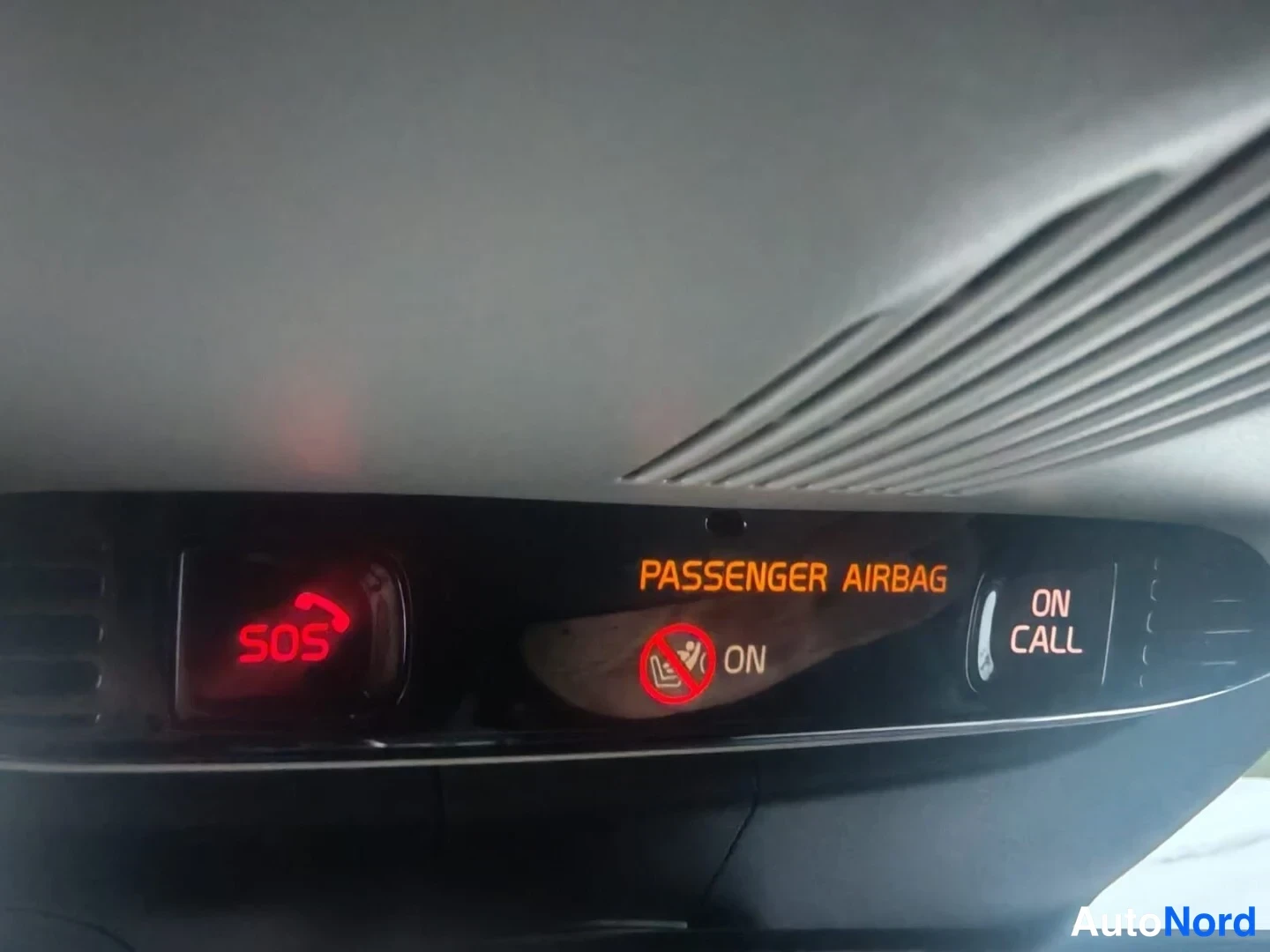 Ohjaamo: Kuva ohjaamon katto-osasta. Punainen SOS-valo on syttynyt, ja keskellä on teksti PASSENGER AIRBAG sekä punainen varoitusvalo merkki matkustajan turvatyyny pääll