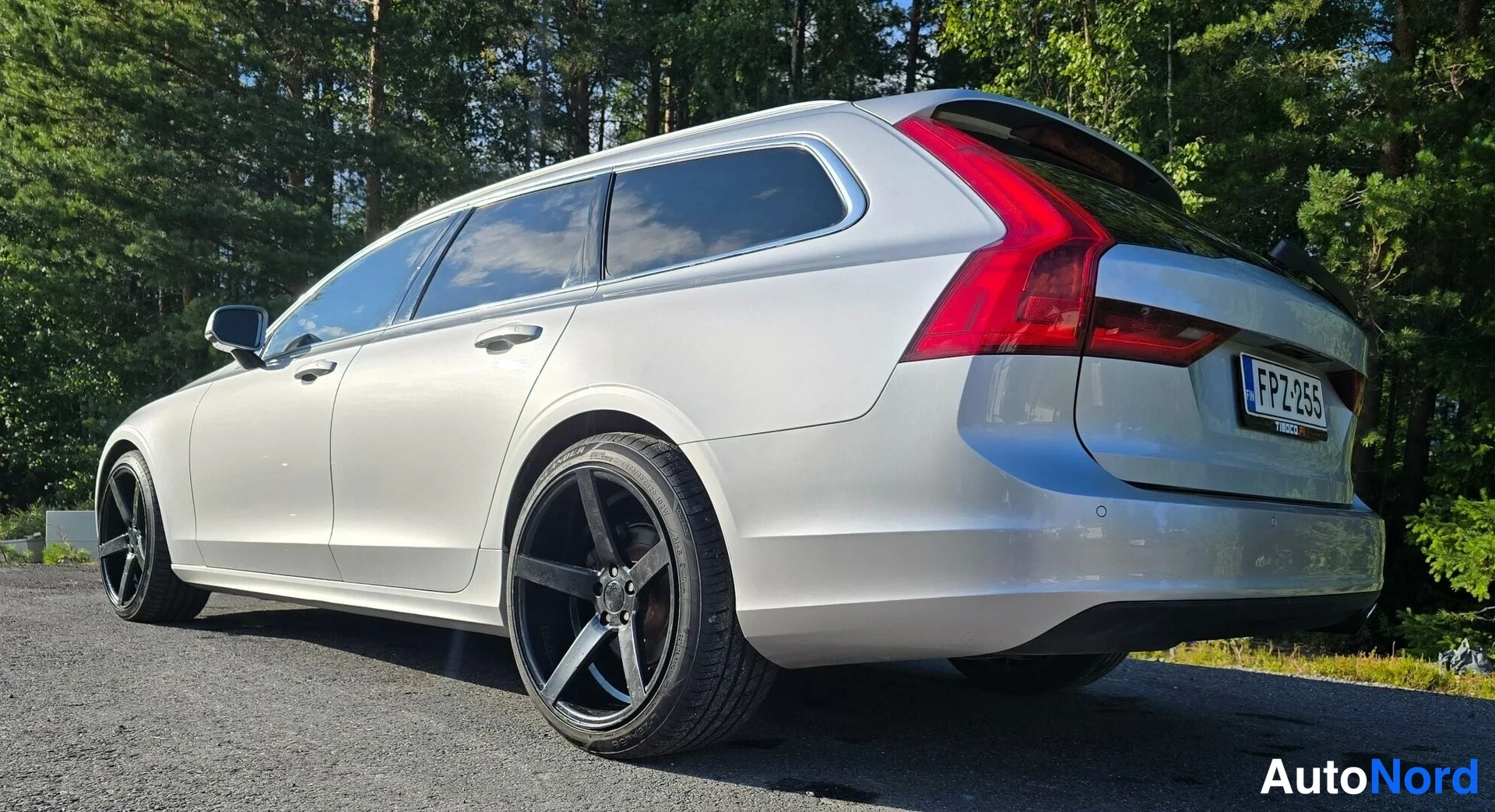 Takaviisto: Silver Volvo estate car photographed from a rear three-quarter angle showing the full side profile and rear end including taillights and license plate, parked o