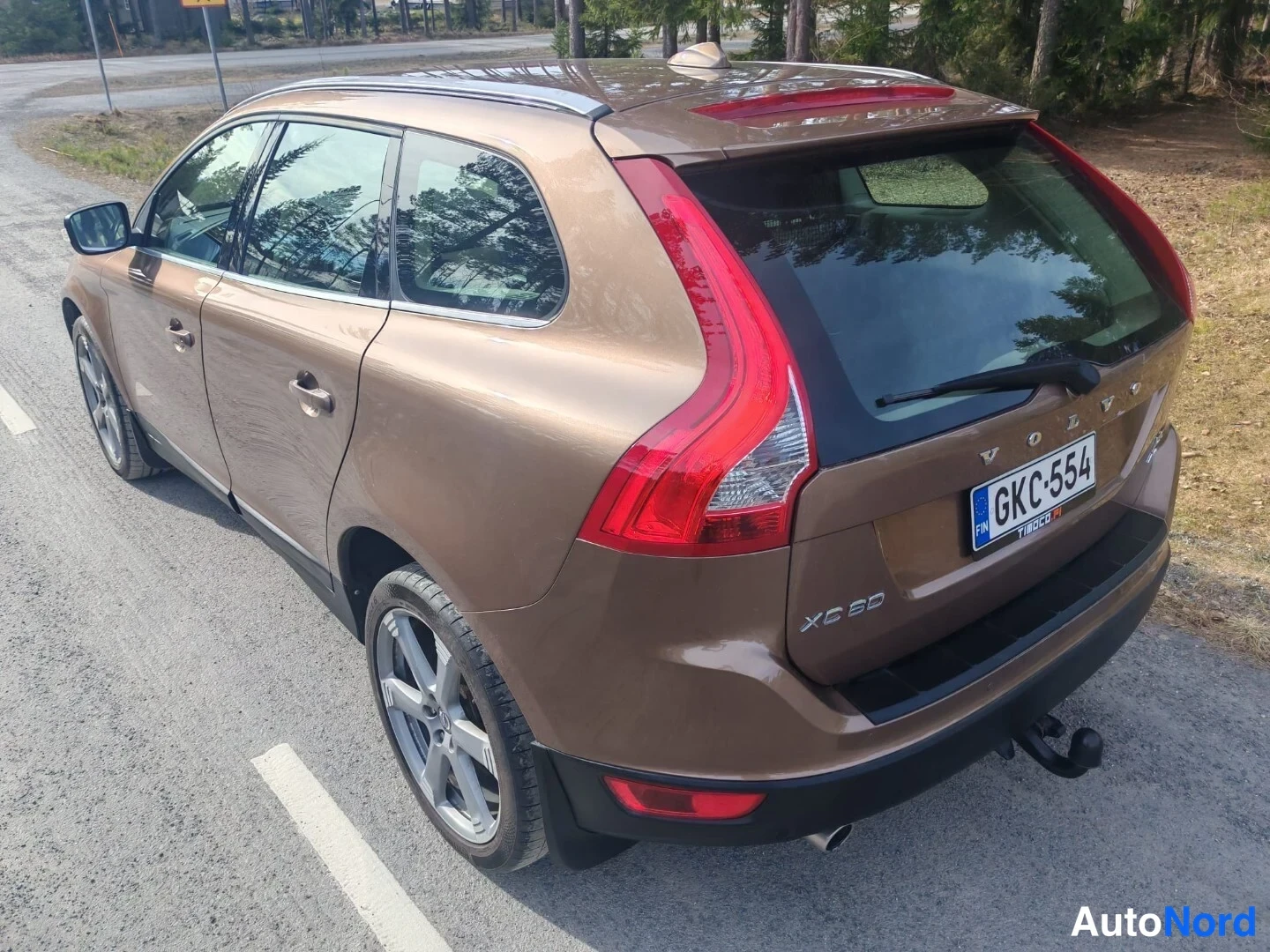 Takaviisto: Ruskea farmarimallinen automme takaa yläviistosta, rekisterikilpi ja XC60-merkintä näkyvät.