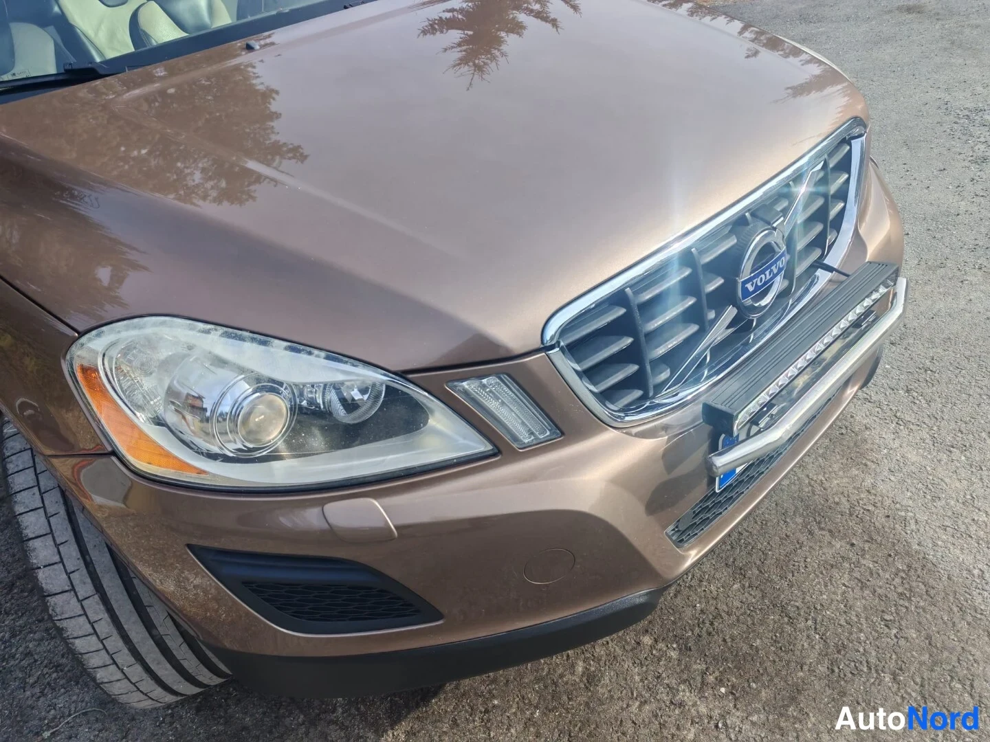 Edestä: Volvo XC60:n keula lähikuvassa: etusäleikkö Volvo-emblemillä, ajovalot ja katolla kiinnitetty LED-tyyppinen lisävalo.