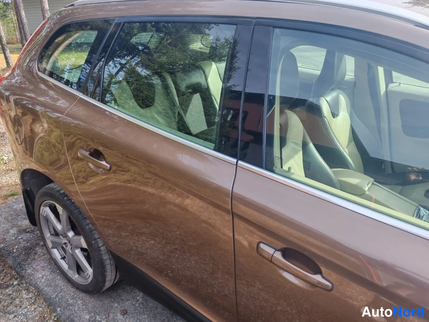 Sivulta: Volvo XC60:n sivuseinä ja takarengas lähikuvassa, ruskea koriväri ja osittain näkyvä sisustan tumma istuin.