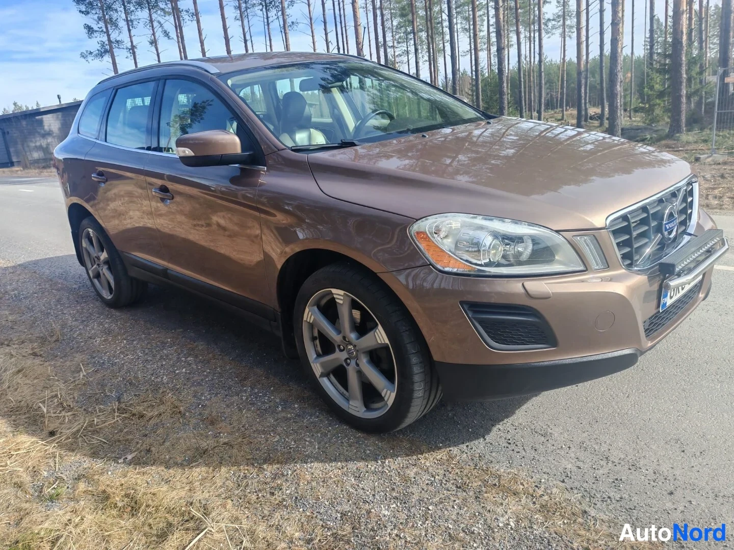 Etuviisto, nokka oikealle: Volvo XC60 edestä oikealta kuvattuna paareilla, ruskea koriväri.