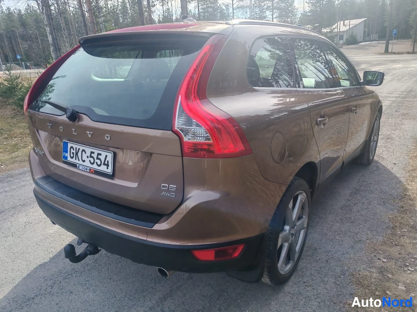 Takaviisto: Takaa ja oikea kulma: ruskea Volvo XC60, rekisterinumero. Vetopyörä ja 'D5 AWD'-logo näkyvät tavaratilan kannessa. Maastopyörät.