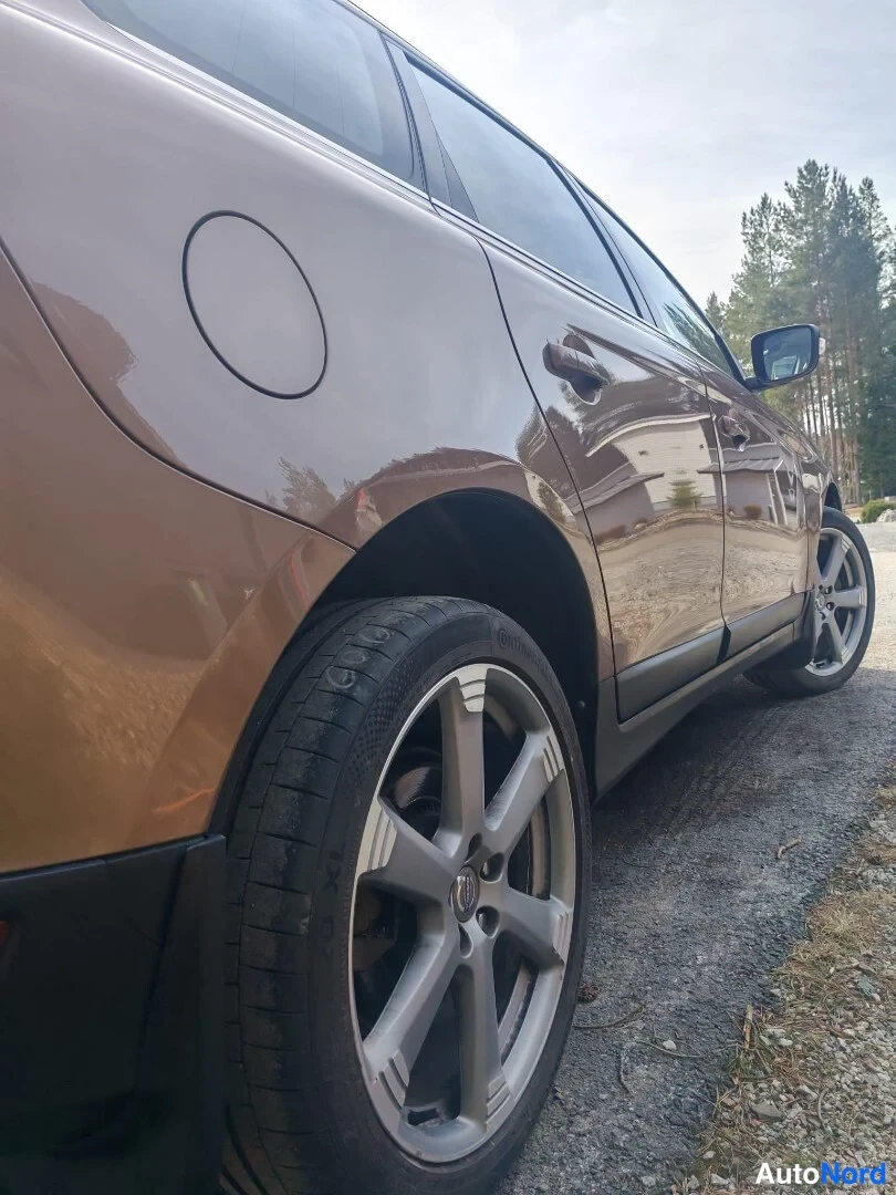 Sivulta: Lähikuva ajoneuvon oikeasta kyljestä. Kuvassa on näkyvissä takapaneelin polttoaineen täyttöaukon luukku, ovet ja hopeanväriset vanteet (ALLOY_WHEELS), joissa on