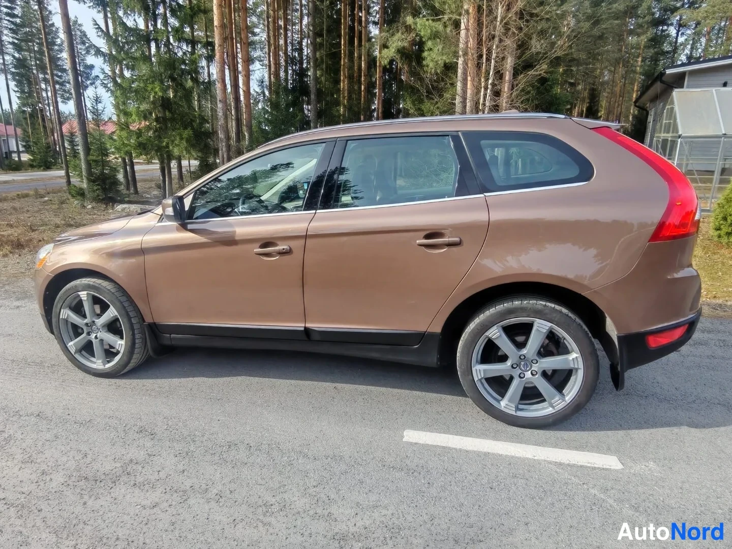 Takaviisto: Ruskea farmarimallinen automme sivulta otettuna asfalttiparkkipaikalla, takavalo näkyy reunassa.