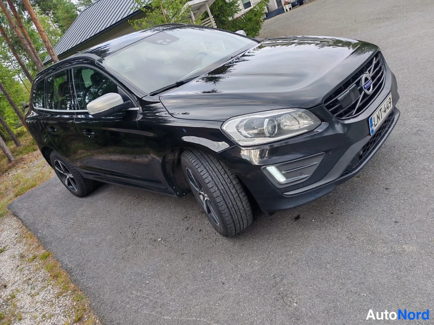Etuviisto, nokka oikealle: Black Volvo XC60 SUV shown from the front three-quarter angle (nose right), highlighting the grille, headlights and driver's side.