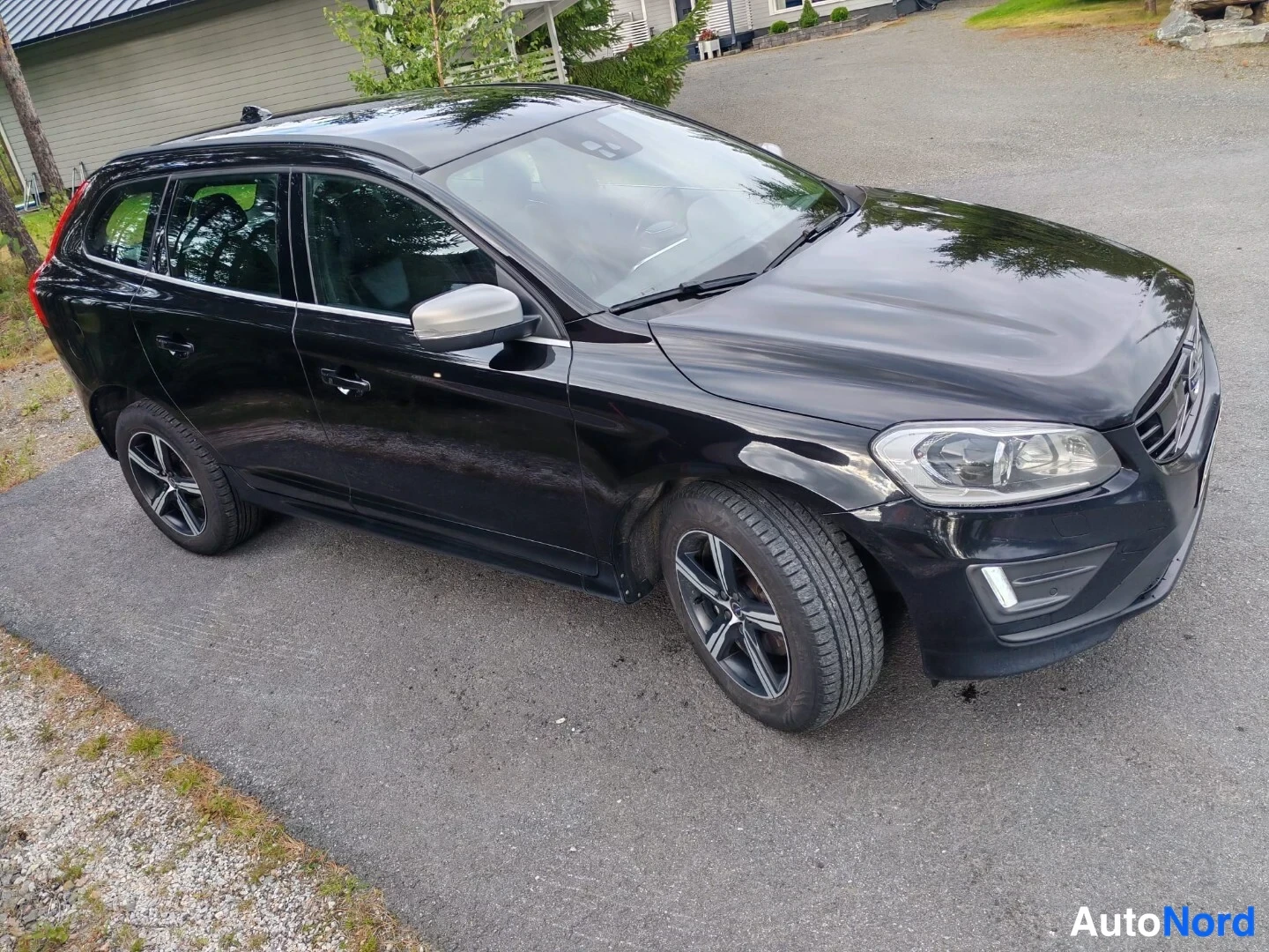 Etuviisto, nokka vasemmalle: Black Volvo XC60 station wagon captured from a high-angle view of the front-left corner, displaying grille, driver's side and wheels.