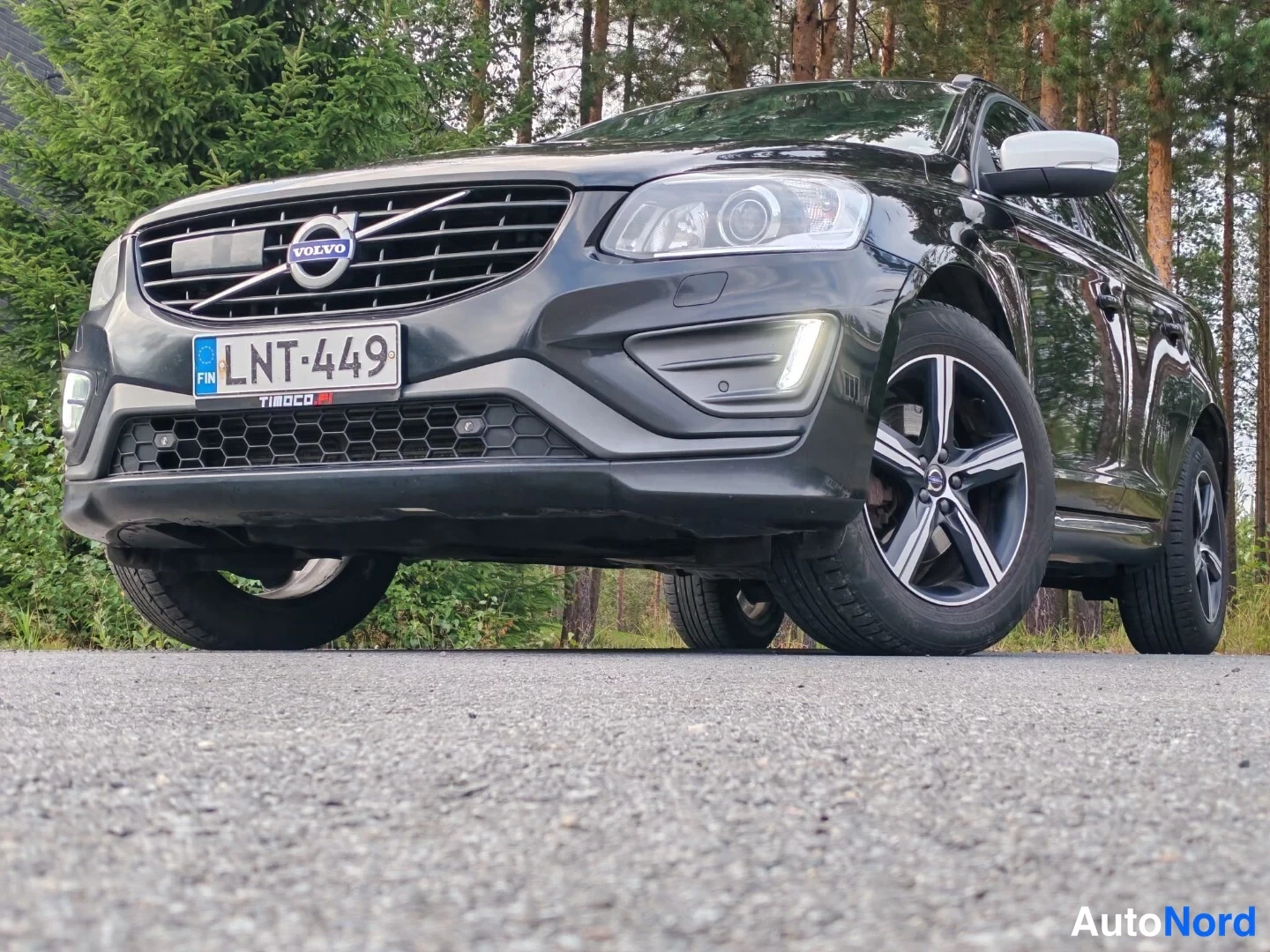 Etuviisto, nokka vasemmalle: Musta Volvo XC60 matalalta kuvattuna edestä vasemmalta; rekisterikilpi ja Tboco-teksti kilven alla.