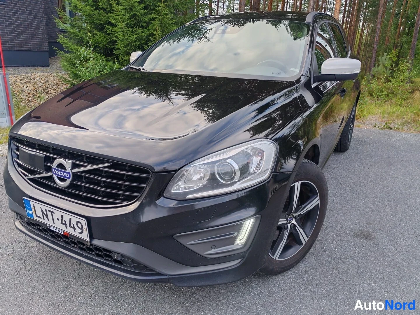 Etuviisto, nokka vasemmalle: Musta Volvo XC60 kolmasosakuvana edestä vasemmalta; kiiltävä konepelti, rekisterikilpi.