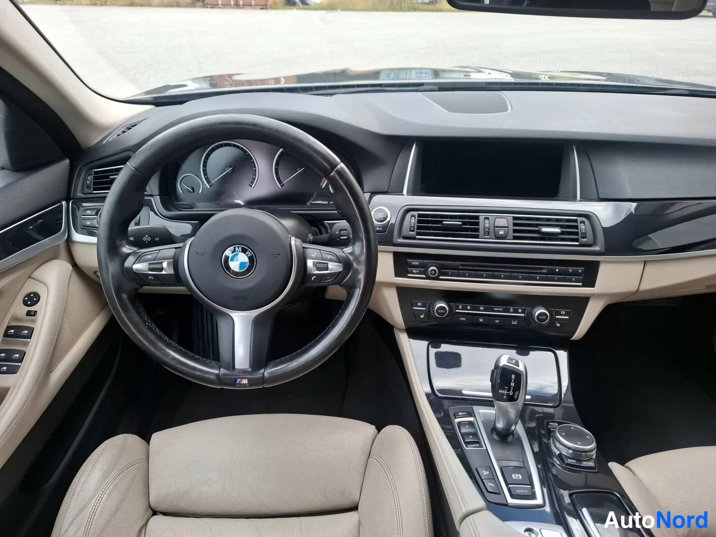 Etuistuimet: Direct view of the driver's cockpit. The steering wheel features an M logo badge on its lower rim. Air conditioning vents and buttons for climate control are lo