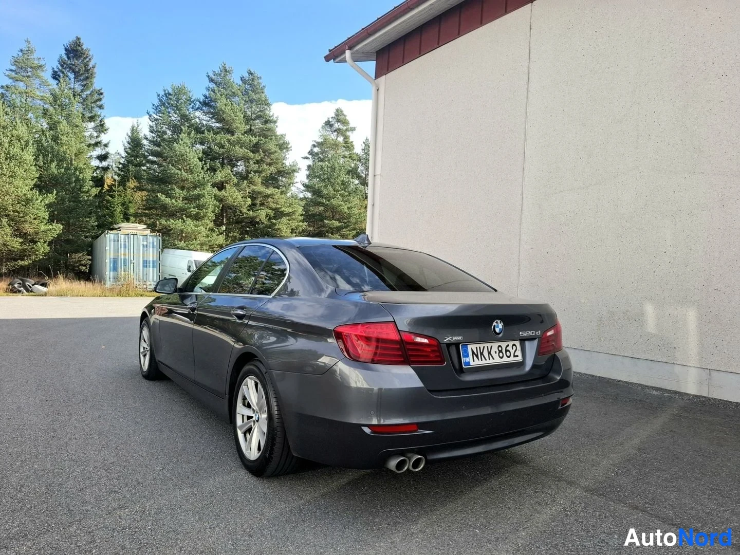 Takaviisto: Tummanharmaa BMW-sedan takakolmannes oikealta, rekisteritunnus, kaksoispakoputki näkyvissä.