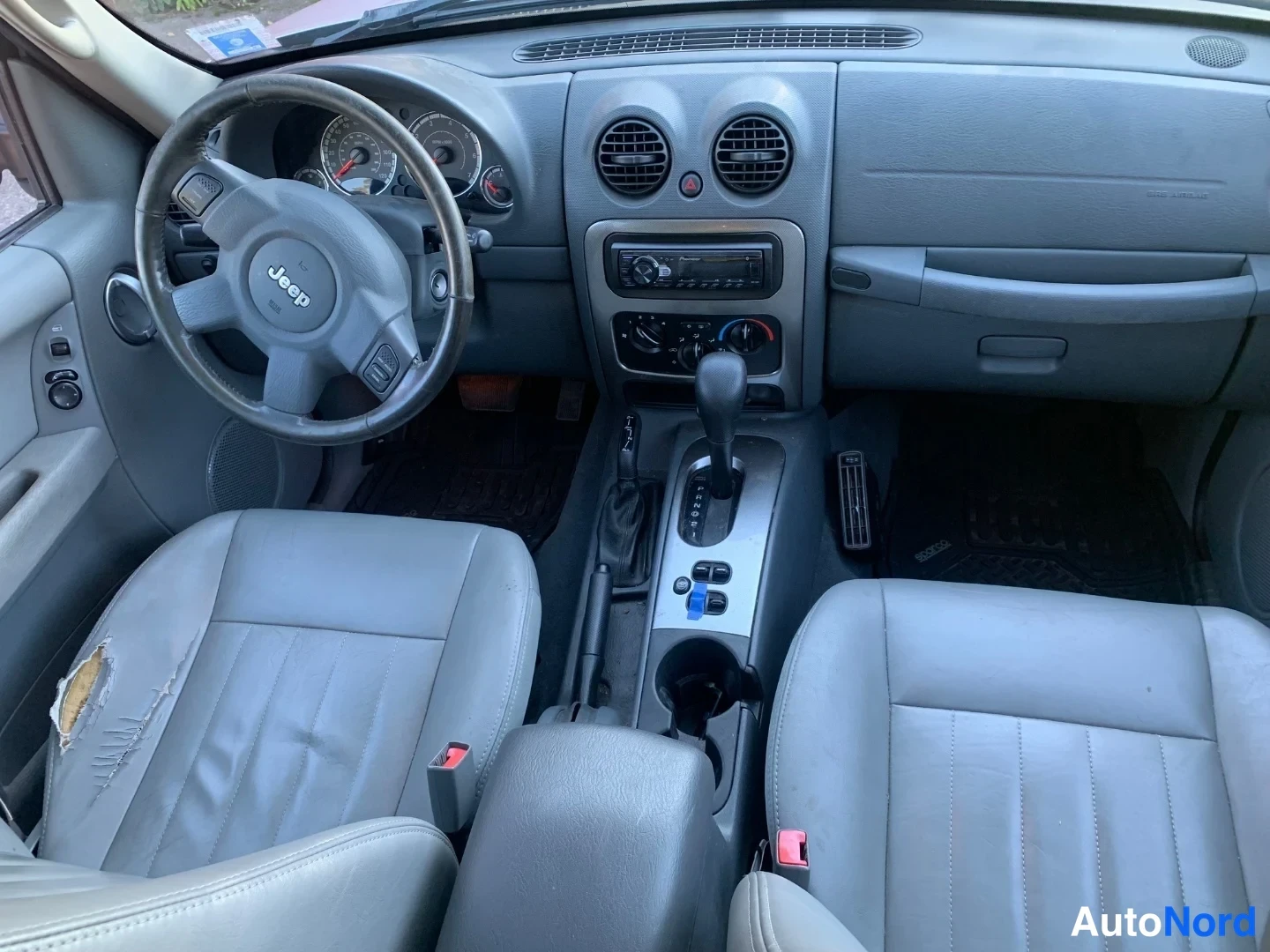 Muu: Ohjaamo ylhäältä: Jeep-ohjauspyörä, kojelauta, radio, automaattivaihteen valitsin ja kaksi etuistuinta.