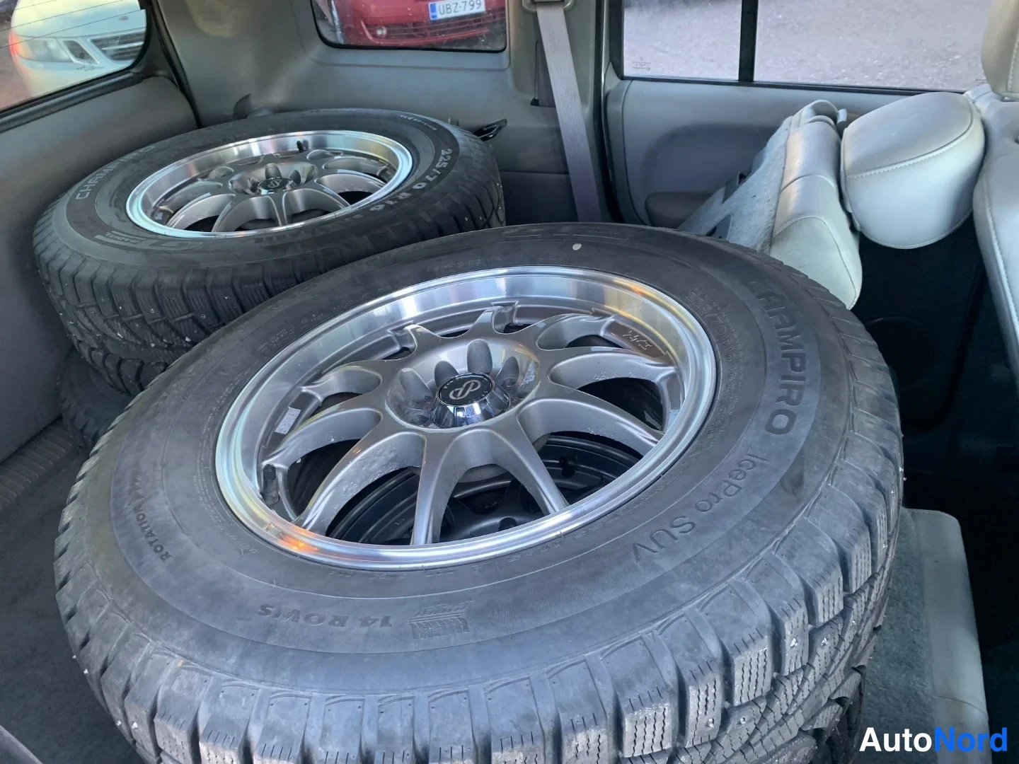 Takaa: Kaksi talvirengasta CHAMPIRO IcePro SUV -merkkinä alumiinivanteilla tavaratilassa, vaaleat takaistuimet näkyy taustalla.