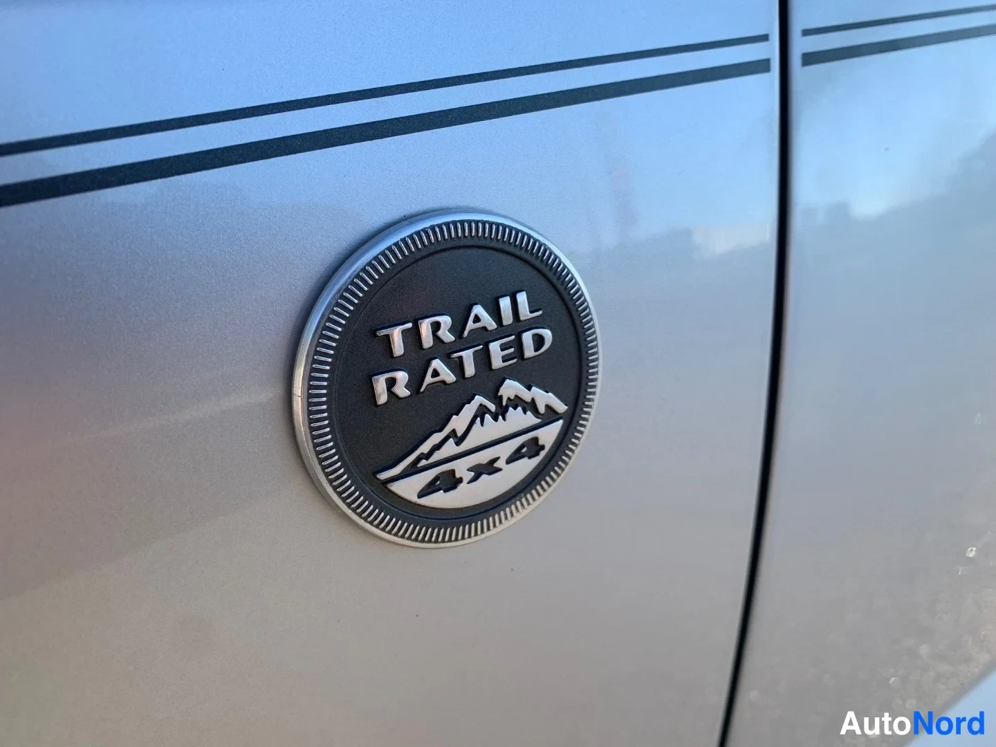 Sivulta: Sivupaneelin lähikuva Jeepin Trail Rated 4x4 -merkinnästä hopeankarmaassa korissa.