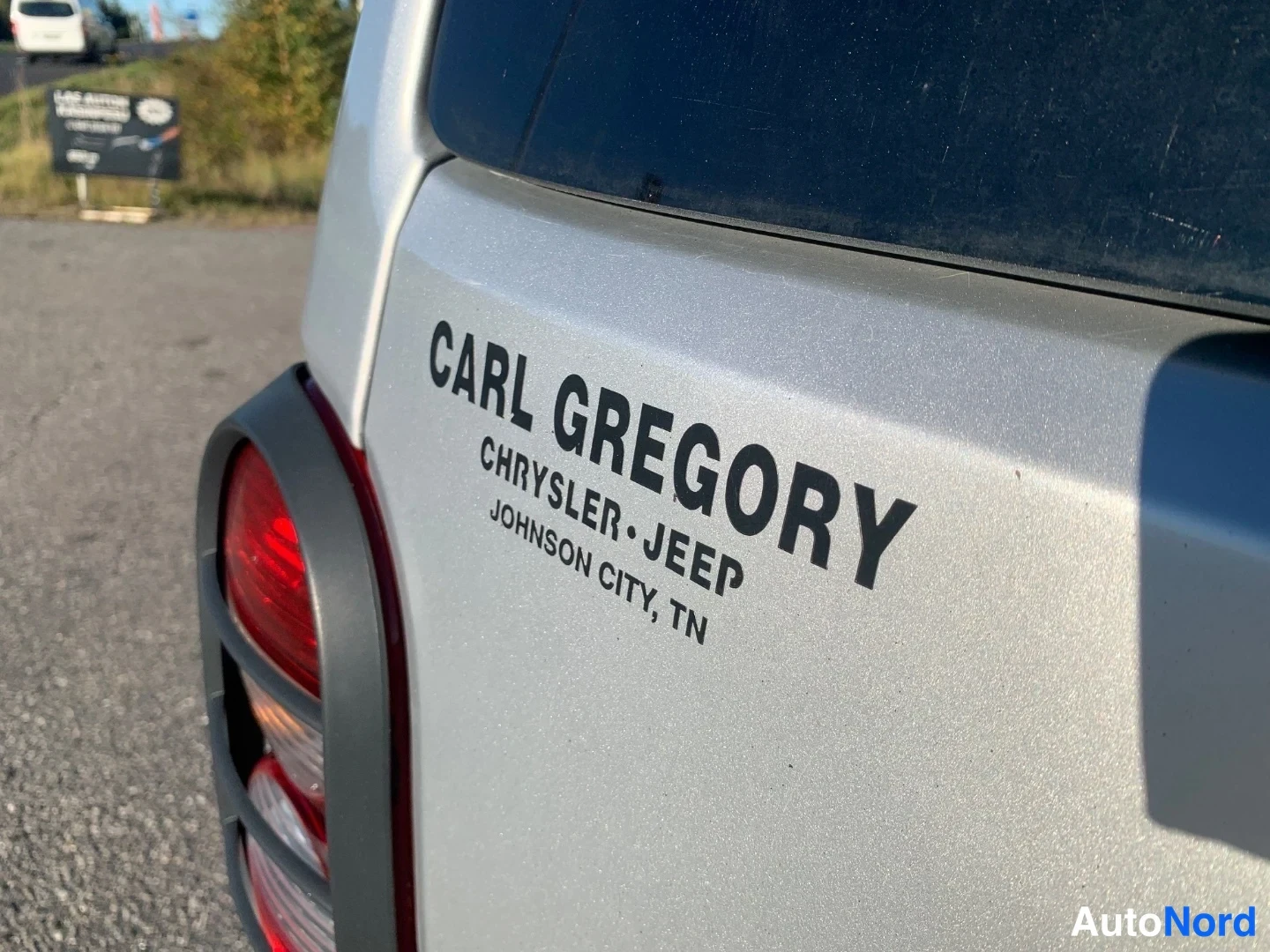Takaa: Auton takaosan lähikuva Carl Gregory Chrysler-Jeep Johnson City, TN -myyjämerkinnällä ja osittain näkyvällä takavalolla.