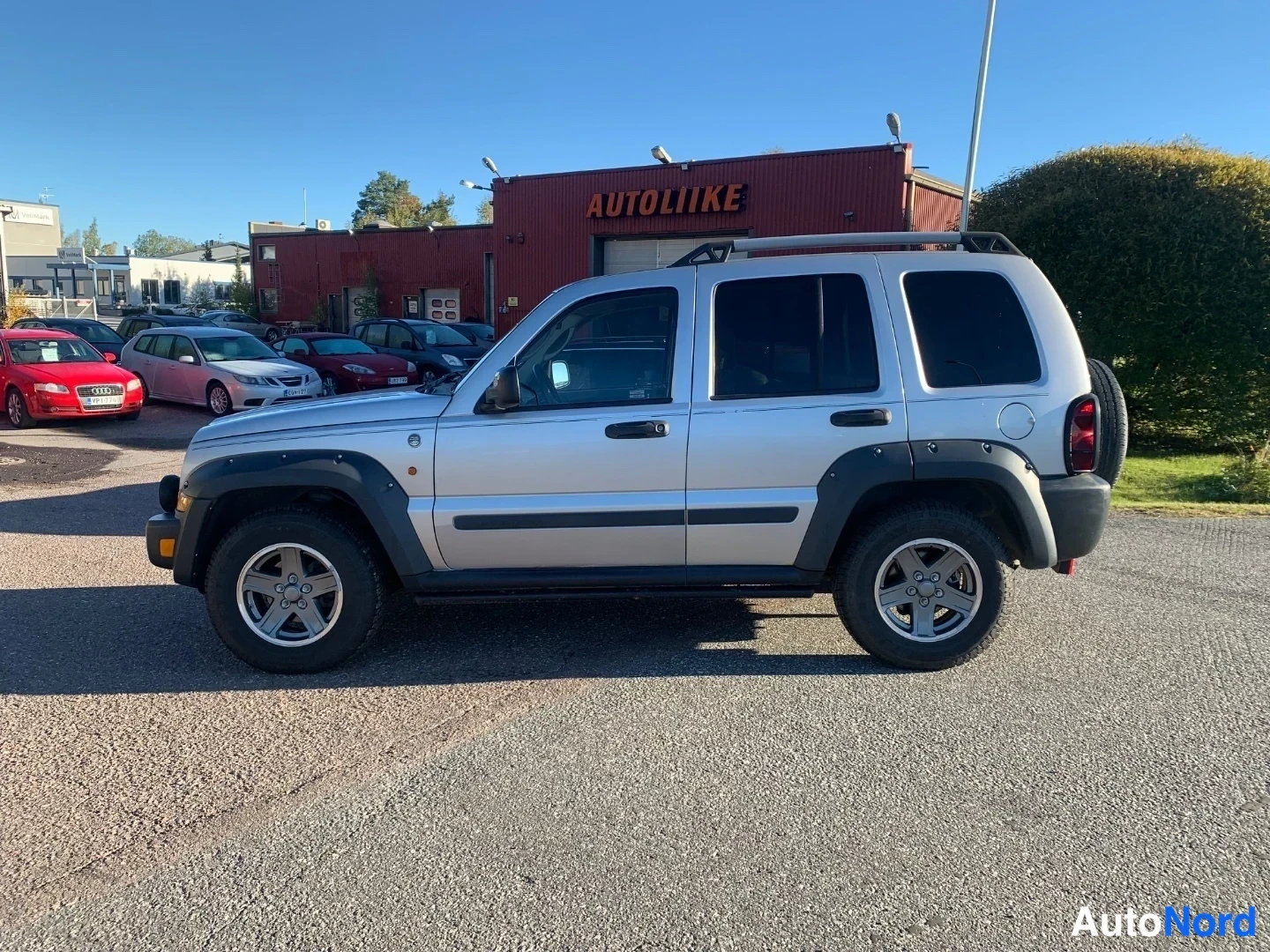 Sivulta: Hopeanharmaa Jeep Liberty -maastoauto sivulta kuvattuna.