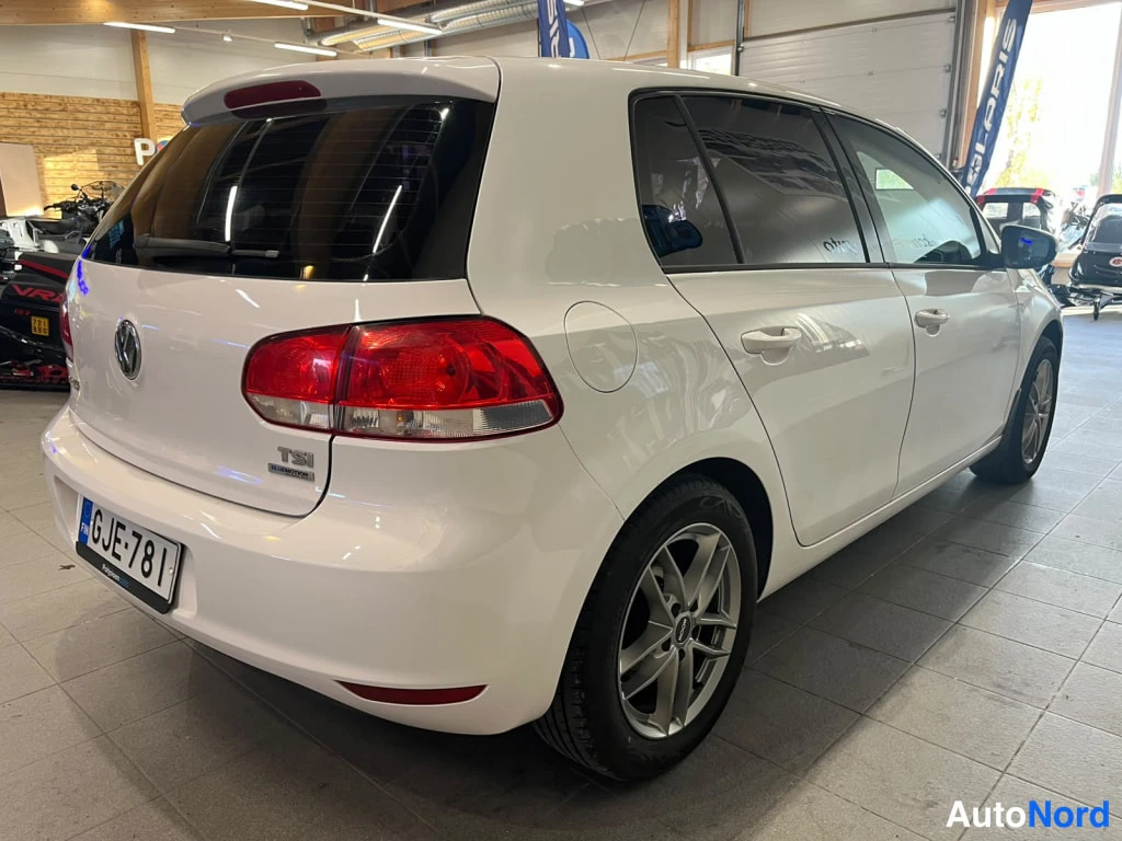 Takaviisto: Auton takaosa ja vasen sivu kolmen neljännesten kulmasta; valkoinen hatchback, tunnistettava rekisterikilpi.