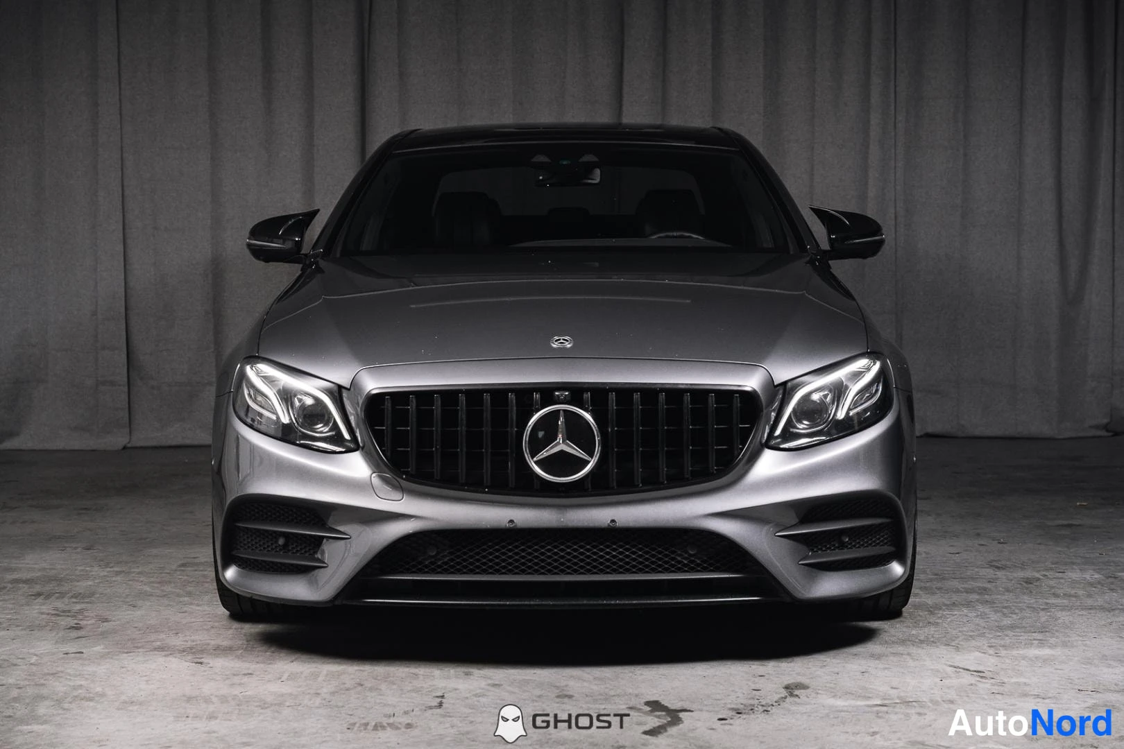 Edestä: Harmaan Mercedes-Benz-sedan keula suoraan edestä kuvattuna, tumma pystysäleikkö ja Mercedes-tähti keskuksessa.