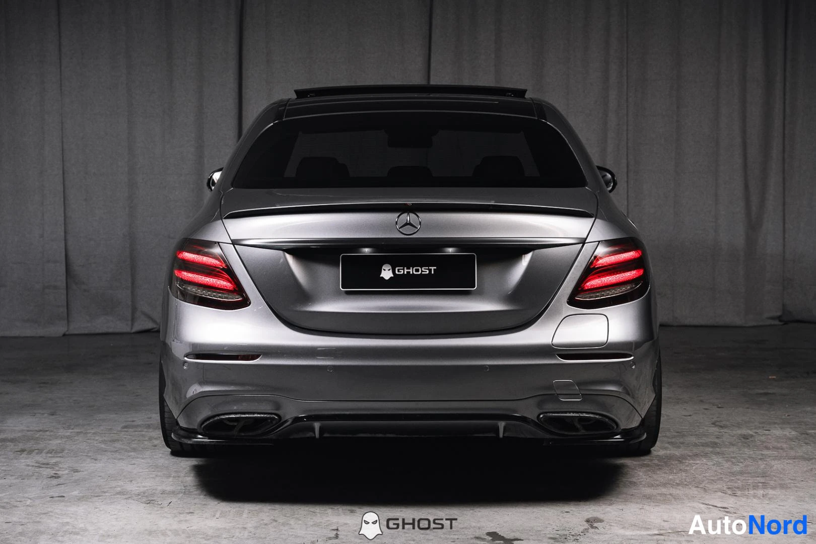 Takaa: Metallinvärisen Mercedes-Benz-sedan takaosa. Takavalot paluvat. Grillillä on Mercedestuntemerkki.