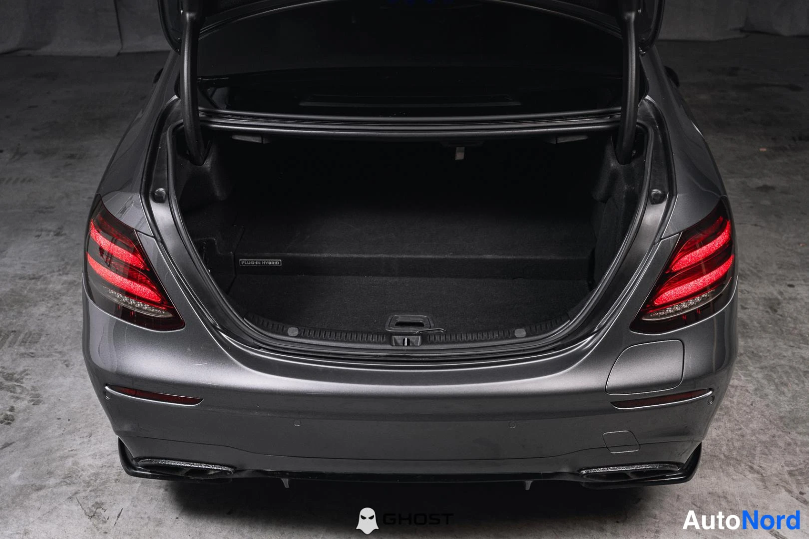 Takaa: Mercedes-Benz E-sarjan sedanin takakansi auki, tummanharmaa runko, LED-takavalot, hiilikuitukatto, matotavaratila